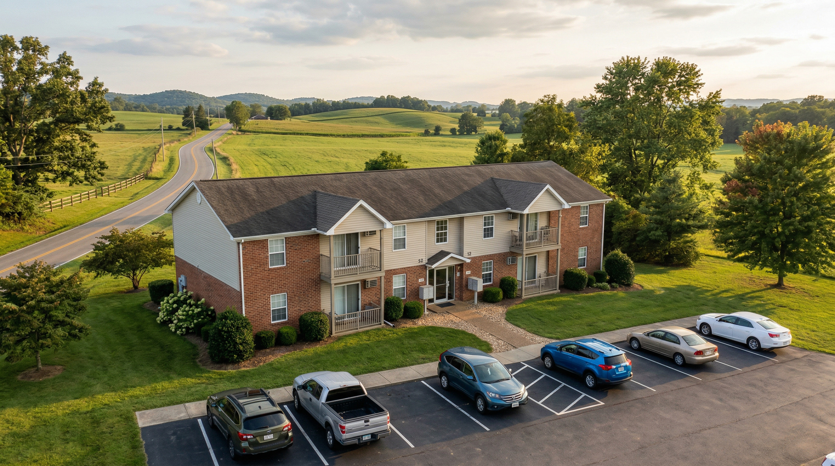 A modest rural multifamily apartment building in a green landscape at golden hour